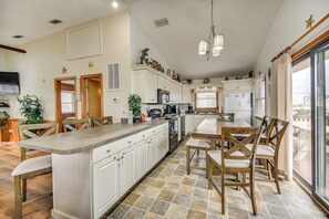A spacious kitchen with a large island, wooden chairs, and a dining table. - Walk to Beach & Dining! Outer Banks Home w/ Grill (Kill Devil Hills)