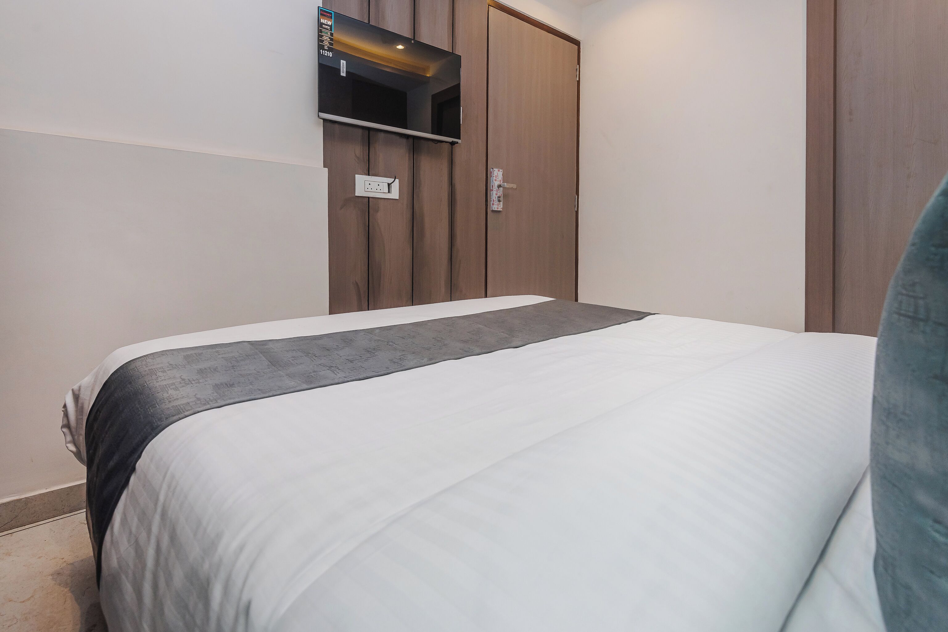 Un dormitorio con una cama, un armario y un televisor montado en la pared.