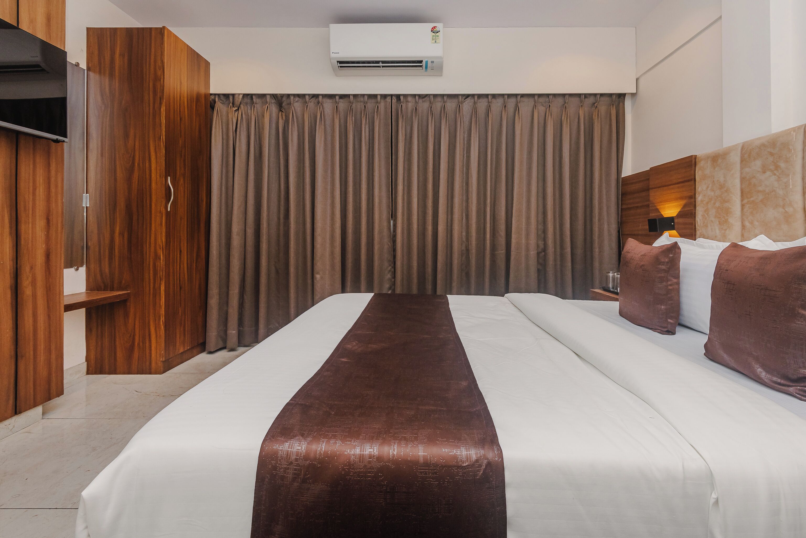 Una habitación de hotel con cama, armario, aire acondicionado y cortina.
