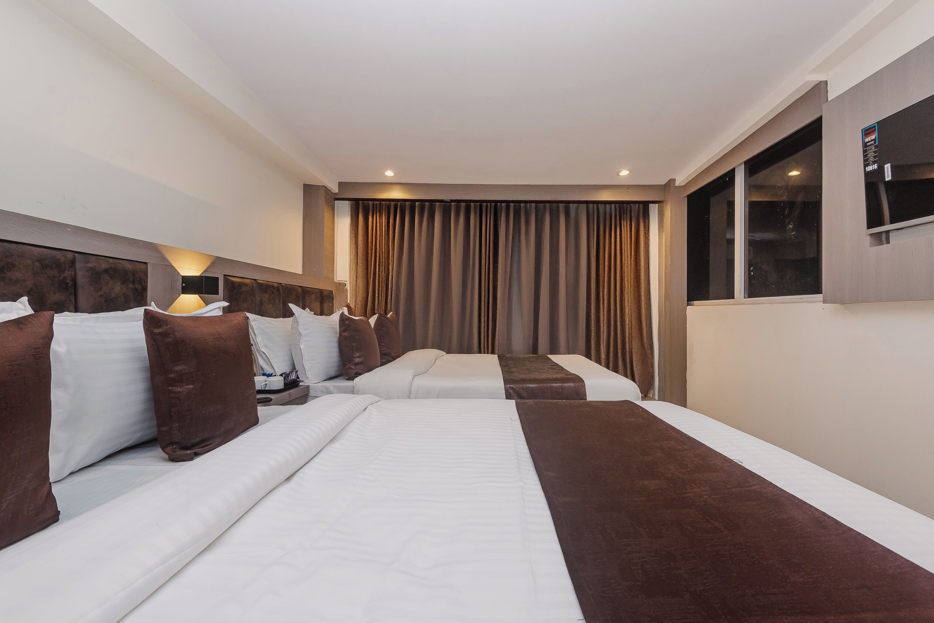 Habitación de hotel con dos camas, un ventanal grande y una cortina.