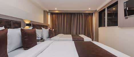 Une chambre d’hôtel avec deux lits, une grande fenêtre et un rideau.