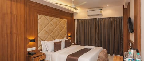 A hotel room with a bed, bedside table, nightstand, and a desk with a chair.