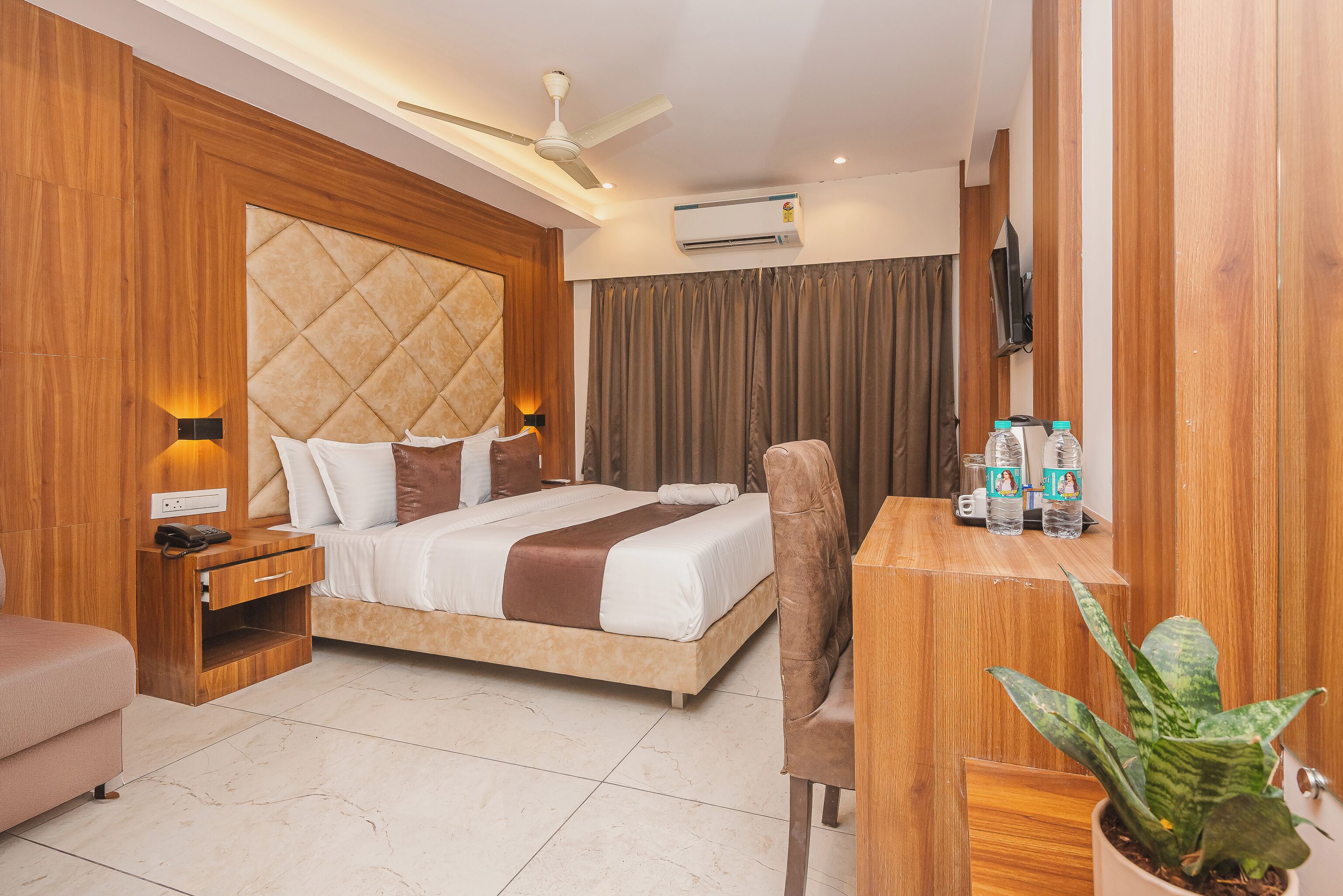 Une chambre d’hôtel moderne équipée d’un lit, d’une table de chevet, d’une chaise, d’un bureau et d’une plante en pot.