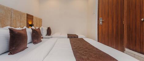 A hotel room with two beds, a wooden wardrobe, and a ceiling fan.