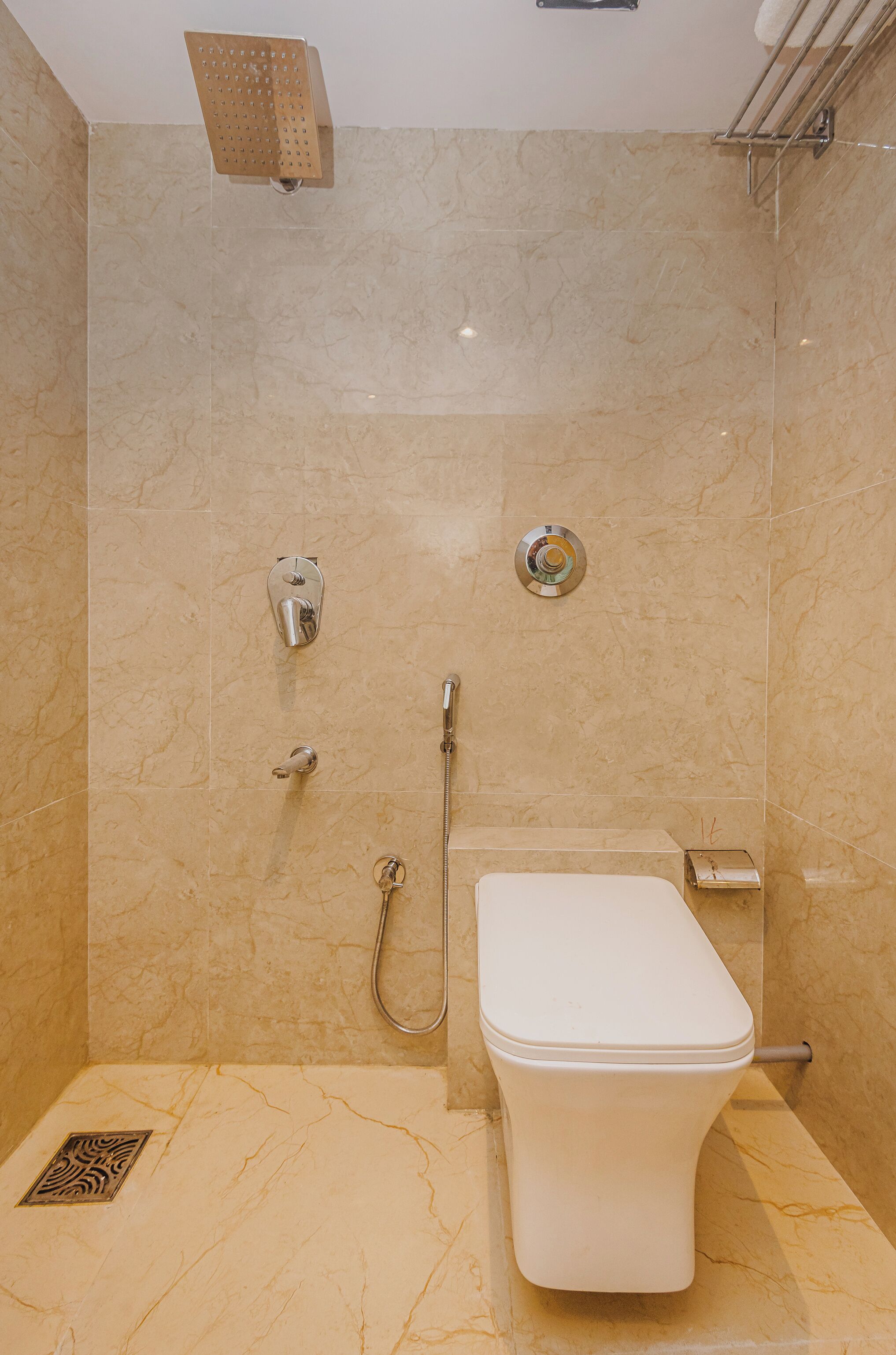 A bathroom with a shower, toilet, and a towel rack.