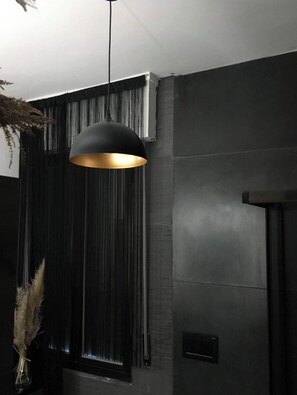 A modern interior with a pendant light, a window with vertical blinds, and a wall-mounted switch. - Penthouse 19 with panoramic view (Montecatini Terme)