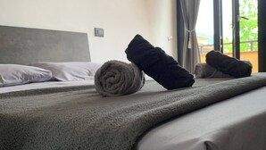 Ett hotellrum med en säng, en hoprullad handduk och en svart handduk på sängen.