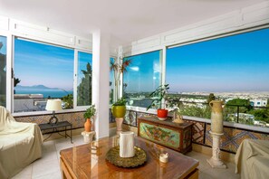 A balcony with a view of the city and sea, furnished with a table, chairs, and potted plants. - Charming 2 Bedroom Apartment in Sidi Bou Said with Ocean Views (sidi Bou Said)