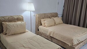 Hotellihuone, jossa on kaksi sänkyä, lamppu, ilmastointilaite ja verho.