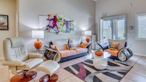 A modern living room with a sofa, armchairs, a coffee table, and abstract wall art.