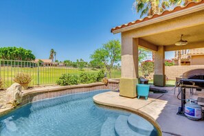 Ein Schwimmbad mit Terrassenbereich, einem Grill und Blick auf einen Golfplatz.