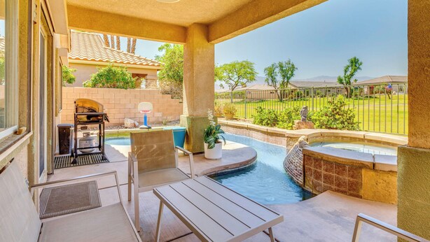 A covered outdoor area with a pool, seating, and a view of a residential neighborhood.