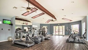 A spacious gym with multiple treadmills, elliptical machines, and free weights.