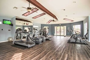 Ein geräumiges Fitnessstudio mit mehreren Laufbändern, Crosstrainern und Kurzhanteln.