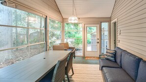 Eine überdachte Terrasse mit Esstisch, Stühlen, einer Couch und einem Deckenventilator.