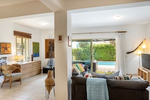 Ein Wohnzimmer mit einer Couch, einem Fernseher und Blick auf einen Pool.