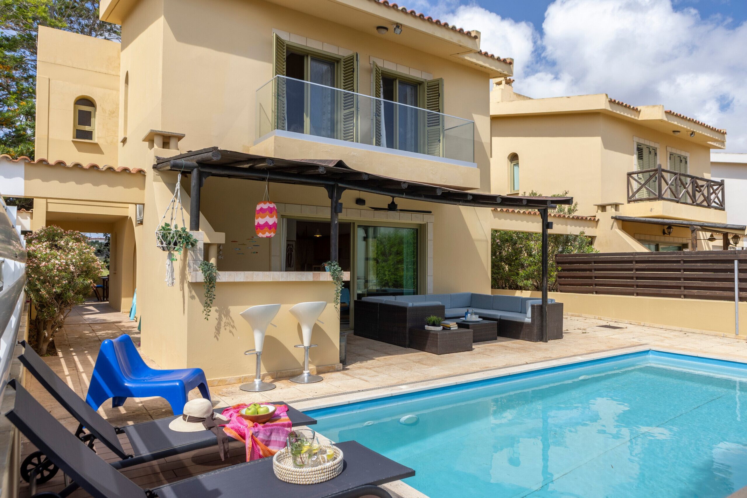 Une maison moderne dotée d’une piscine, d’un espace salon extérieur et d’un patio couvert.