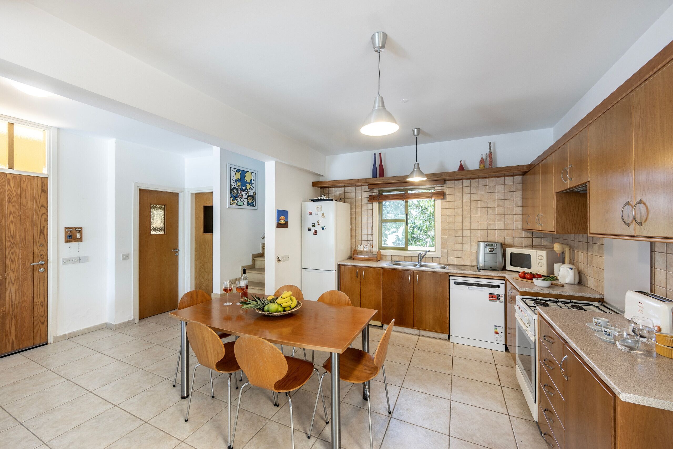 A kitchen with a dining table, chairs, a refrigerator, a microwave, and a stove.