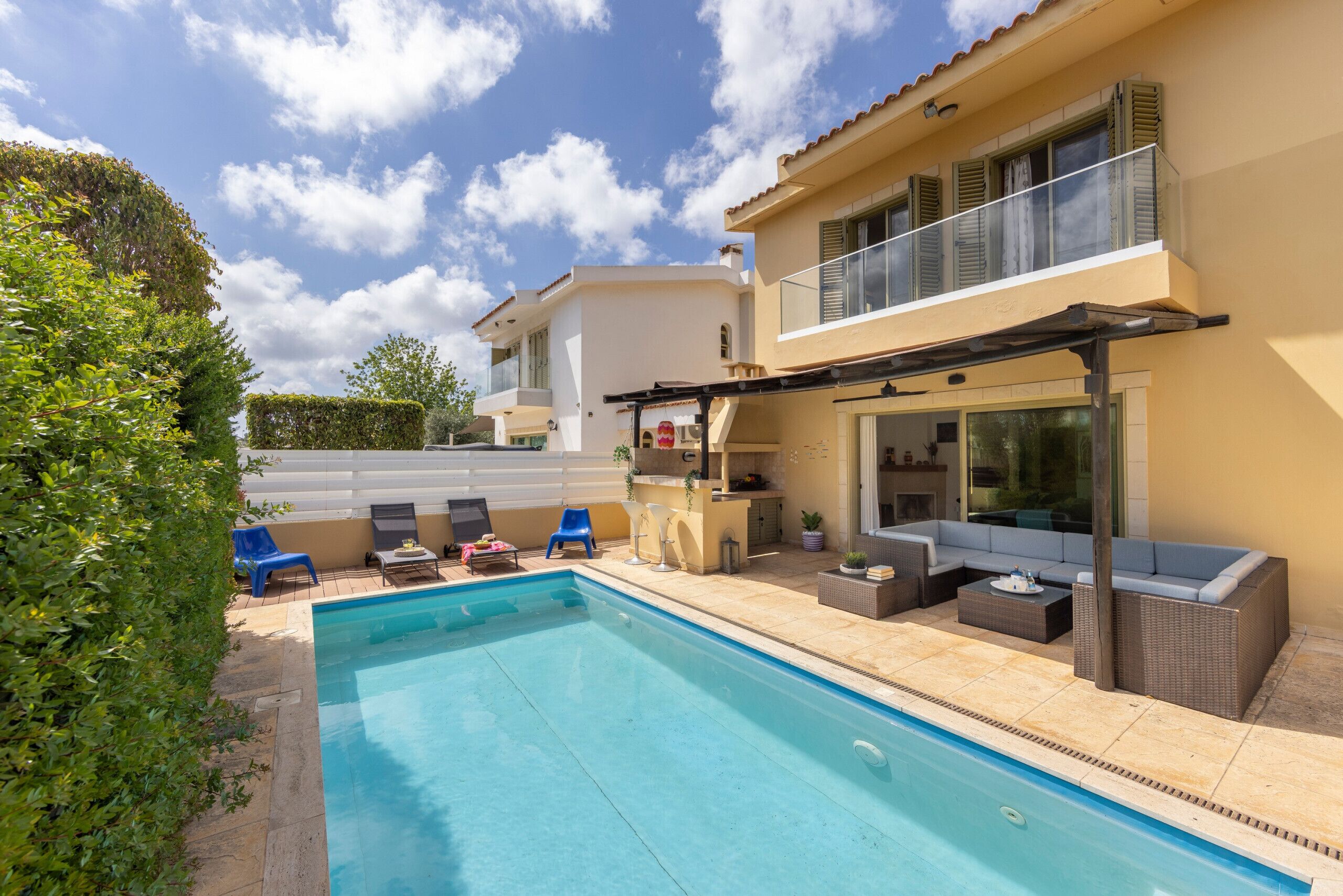 Una casa moderna con piscina, area salotto all'aperto e un balcone.