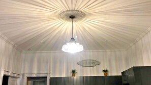 Ein Zimmer mit einer Chandelüstere, einem Willkommensschild und zwei Blumentöpfen.