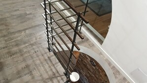 Een wenteltrap met houten treden en metalen leuning, die naar een lager gelegen niveau leidt.