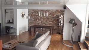 Een moderne woonkamer met een stenen muur, een houten eettafel en een bank.