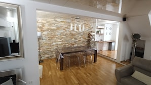 Een moderne leefruimte met een eethoek, een stenen muur en een keuken op de achtergrond.