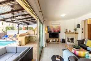 Ein offener Wohnbereich mit Pool, Kamin und Fernseher.