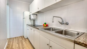 A kitchen with white cabinets, a stainless steel sink, and a microwave. - RIELLS: Fully renovated seafront apartment (L'Escala)