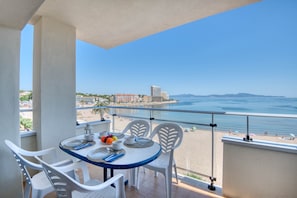 Ein Balkon mit Tisch für Zwei, mit Blick auf Strand und Meer.