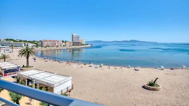 A beach with a restaurant, a hotel, and a view of the sea. - RIELLS: Fully renovated seafront apartment (L'Escala)
