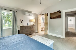 A bedroom with a bed, dresser, lamp, and a sliding door leading to another room. - Walk to Stetson and Historic Downtown DeLand! (DeLand)