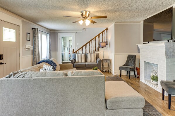A living room with a sectional sofa, a fireplace, a ceiling fan, and a staircase leading to another room. - Walk to Stetson and Historic Downtown DeLand! (DeLand)