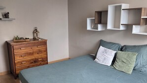 Camera da letto con un letto, una cassettiera in legno ed alcune mensole a parete.