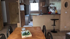 Zona pranzo con tavolo in legno, sedie e vassoio con candele.