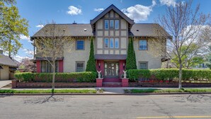A two-story house with a symmetrical facade, a central entrance with steps, and a driveway leading to the front door. - Grand Multi-Unit Estate: 2 Mi to Dtwn Minneapolis! (Minneapolis)