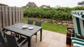 An outdoor patio with a table set for four, surrounded by wicker chairs.