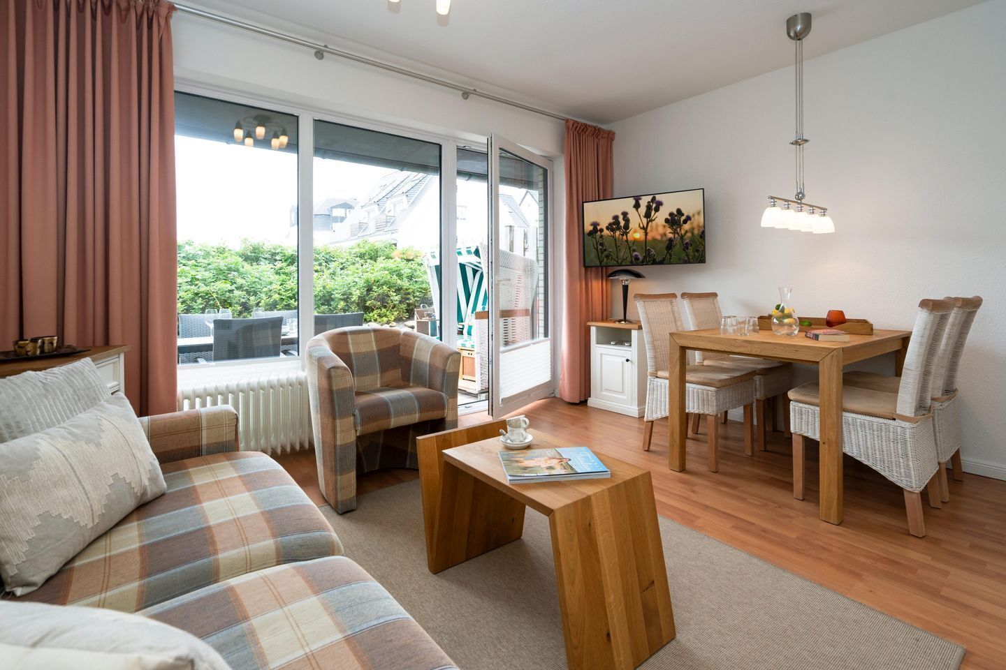 A cozy living room with a sofa, armchair, wooden coffee table, and a dining table with chairs.