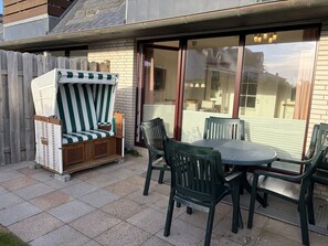 Un patio con una silla de mimbre, una mesa y sillas.
