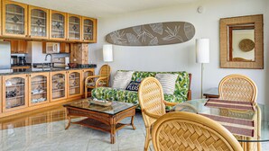 Een woonkamer met een bank, stoelen, een salontafel en houten kasten.