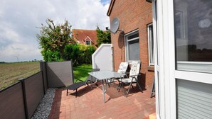 Eine Terrasse mit Tisch und Stühlen, eine Satellitenschüssel und ein Ziegelgebäude mit Garagentor.