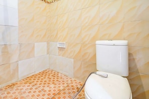 A bathroom with a toilet, a hand dryer, and a tiled floor.