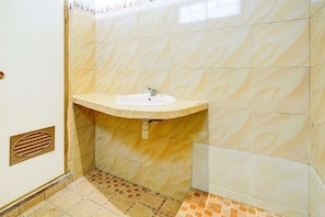 A bathroom with a sink, tiled walls, and a patterned floor.