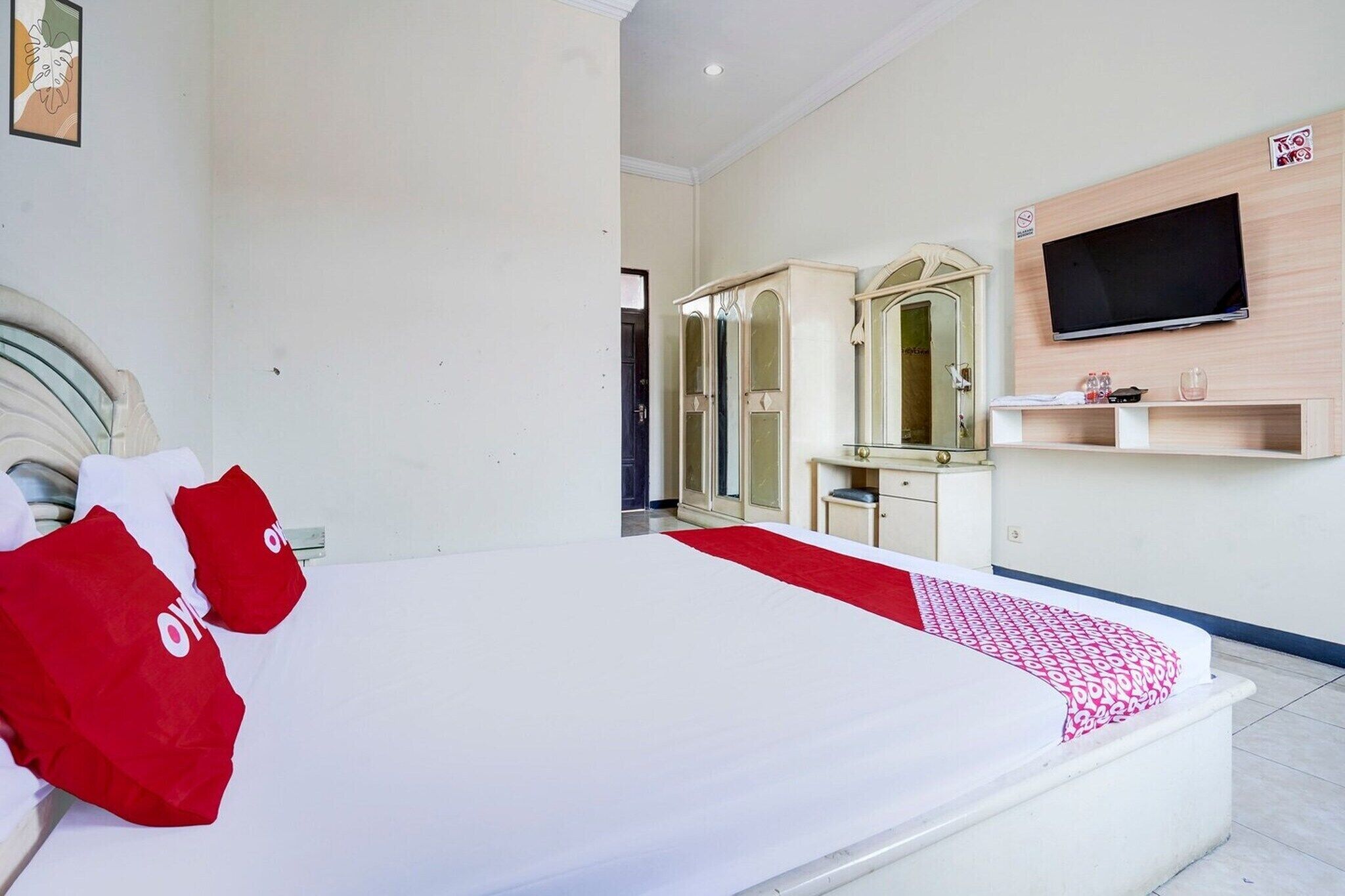 A hotel room with a bed, a TV, a mirror, and a wardrobe.