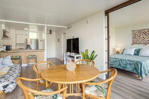 Ein modernes Wohnzimmer mit Essbereich, einer Küche und einem Schlafzimmer mit Bett und Fernseher.