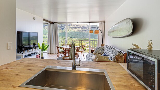 Una cucina moderna con un'ampia finestra, un'area pranzo e un soggiorno con vista sulle montagne.