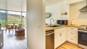 Una cucina moderna con vista su un paesaggio montuoso, un'area pranzo con mobili in vimini e un'ampia finestra.