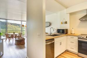 Eine moderne Küche mit Blick auf eine Berglandschaft, eine Essecke mit Korbmöbeln und ein großes Fenster.