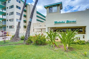 Un edificio con un letrero que dice 'Makahoa Shores', rodeado de un césped cuidado y palmeras.