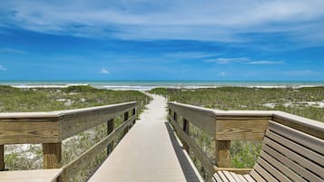 A wooden boardwalk leading to a beach with a clear sky.